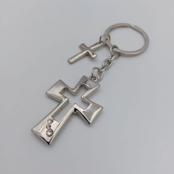 llavero compuesto por una anilla y dos cruces una de ellas más pequeña y la otra mas grande hueca por dentro y adornada con tres brillantes en la parte inferior